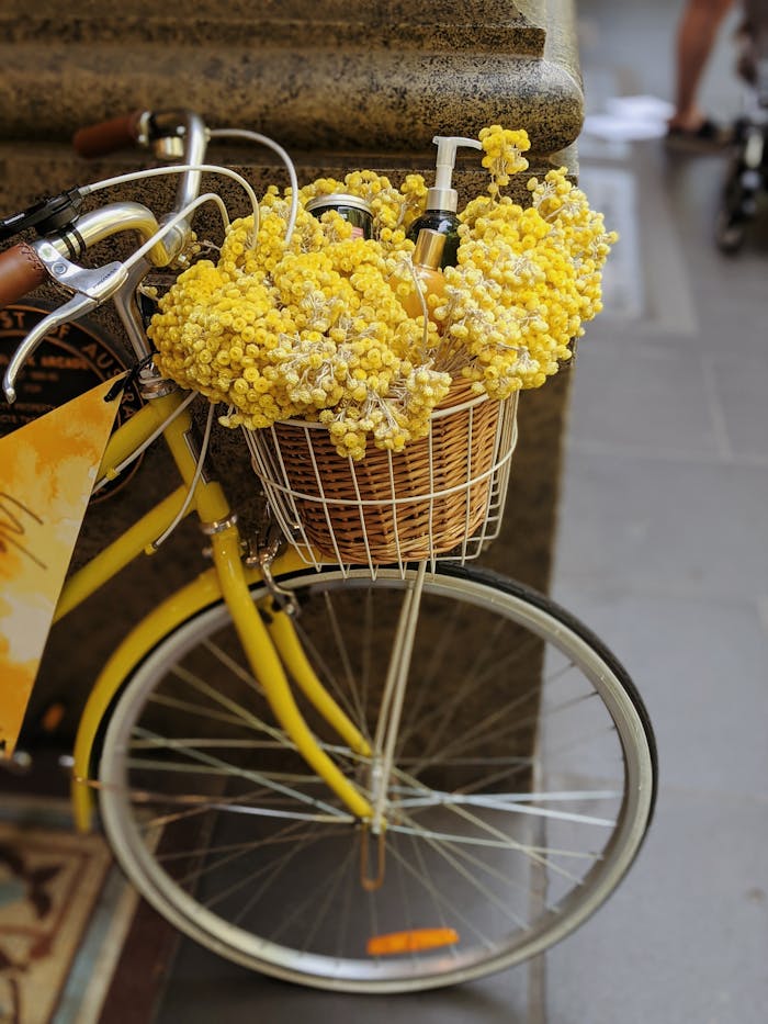 A vintage yellow bicycle adorned with a basket of vibrant yellow flowers on a Melbourne street.